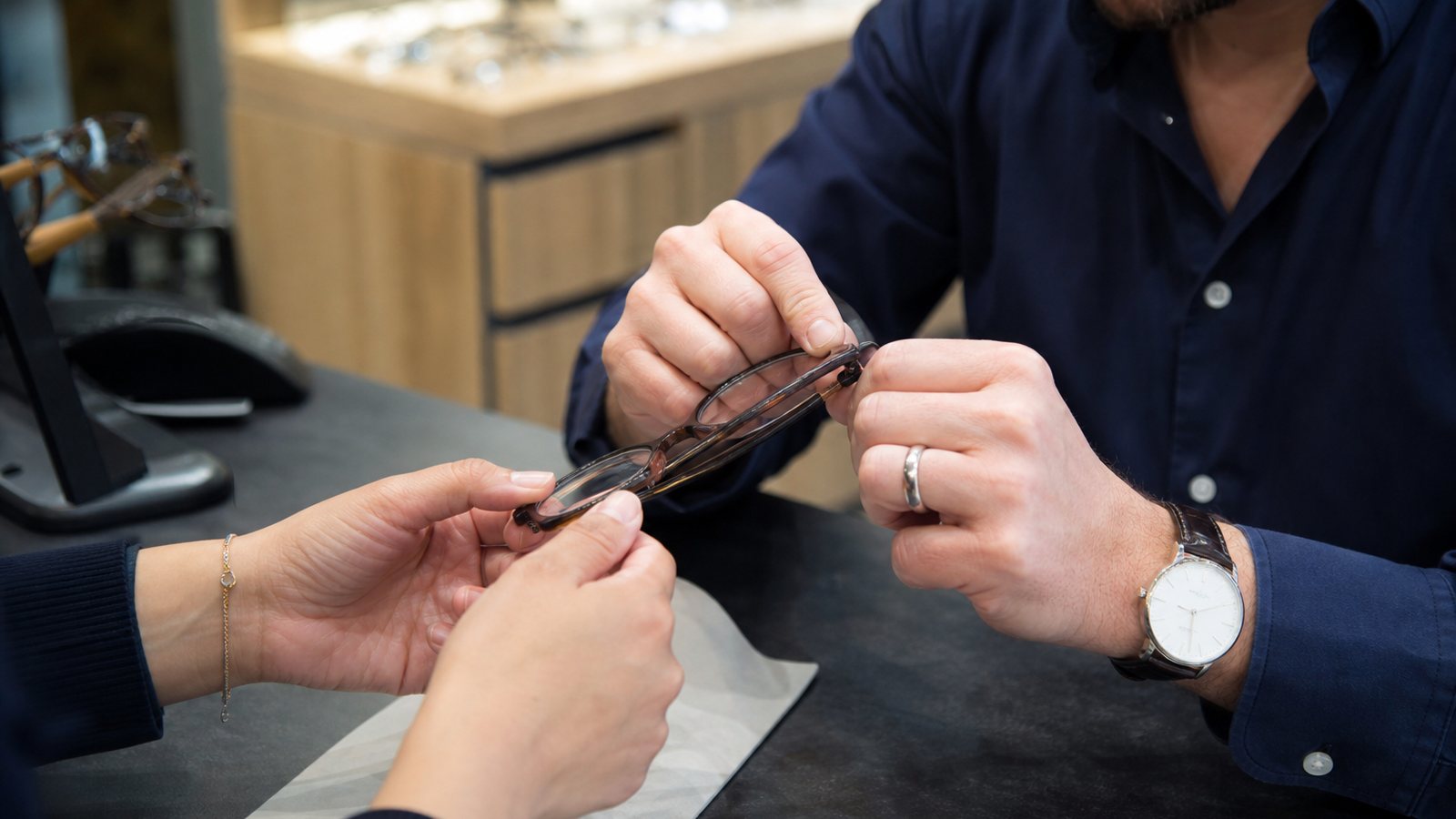 Opticien examinant la monture qu'un client vient de confier pour réparation au comptoir